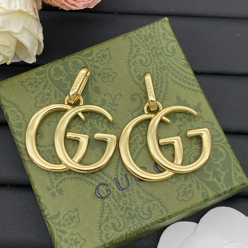 Gold earrings with 'GG' design on a Gucci box