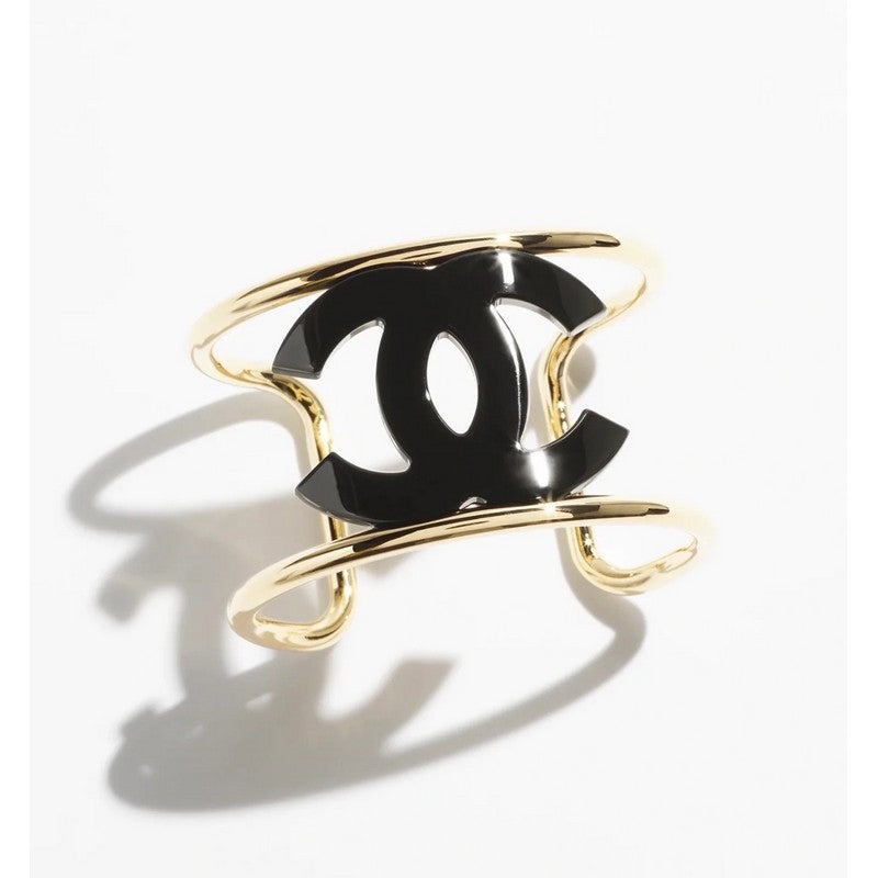 Gold and black bracelet with Chanel logo on a white background